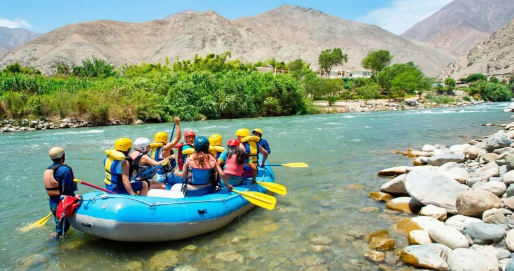 Grupo de turistas haciendo canotaje en el río Cañete en Lunahuaná con montañas al fondo - Full Day con Perú Tours