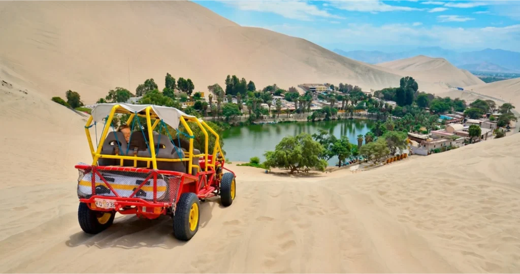 Tubular recorriendo las dunas de arena frente al oasis de la Huacachina en Ica - Full Day Paracas con Perú Tours